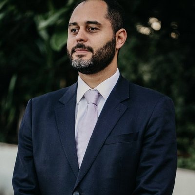 Thiago Alves dos Reis, titular da TR Advocacia, retrato editorial em terno azul-marinho com fundo de jardim.